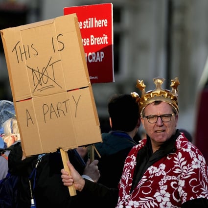 Protestors hold placards in Parliament Square as Britain’s Prime Minister Boris Johnson attends the weekly Prime Ministers’ Questions session in parliament in London on January 12. Johnson has apologised for attending a garden party during Britain’s coronavirus lockdown, but brushed aside opposition demands that he resign. Photo: AP