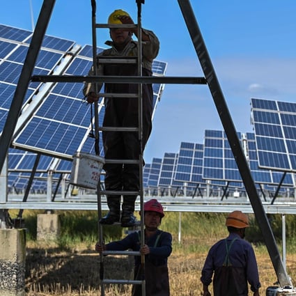 Workers work next to solar panels in an integrated power station in Yancheng city, Jiangsu province, on October 14, 2020. Expect companies focusing on emissions reduction, new forms of energy, and providing the infrastructure for new energy facilities to be among the market leaders next year. Photo: AFP 
