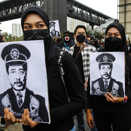 Protesters hold placards displaying the face of Azam Baki. Photo: EPA