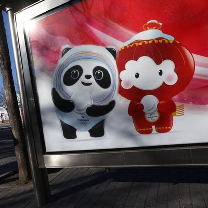 A woman stands near a board with an image of the Beijing Winter Olympics mascots, at a bus stop near the Winter Olympic Village, on January 27. Photo: Reuters