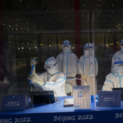 Workers in protective gear at the Beijing Capital International Airport wait to inspect Olympic credentials ahead of the Winter Games. Photo: AP