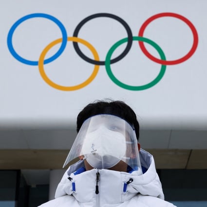 A volunteer stands in front of Olympics Rings at the National Aquatics Centre in Beijing. Photo: Reuters