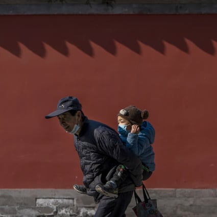 An elderly man carries a young boy at a park in Beijing on February 9, 2021. Births fell in China for the fifth year in a row in 2021, adding to fears that country will soon be left with a reduced and overburdened working-age population. Photo: AP