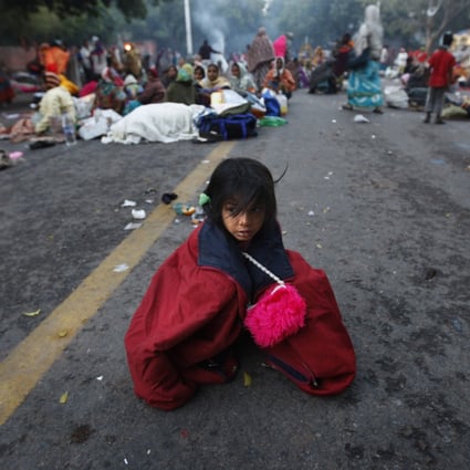 A child near the Indian Parliament, in New Delhi, takes shelter from the wind as protesters arrive in the capital for protests against rising inflation and unemployment. Photo: AP