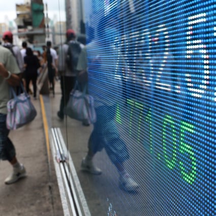 A woman walks past an electronic board in Mong Kok showing the closing Hang Seng Index number in June 2020. Photo: Edmond So