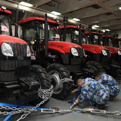 On January 30, PLA Navy personnel fasten tractors on a ship delivering relief supplies to Tonga. Weighing approximately 1,400 tonnes, the latest supplies include mobile homes, tractors, electricity generators, water pumps, water purifiers, food and medical supplies. Photo: Xinhua
