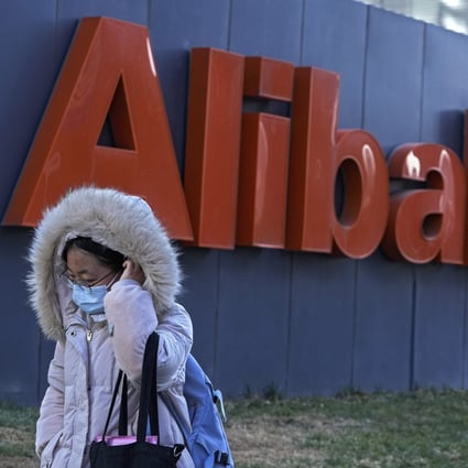 A woman wearing a face mask walks by the offices of Chinese e-commerce firm Alibaba in Beijing. Photo: AP Photo