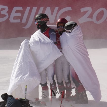 US skier Mikaela Shiffrin (centre) and her teammates stay warm with blankets after losing their semi-final in the mixed team parallel skiing event on Sunday. Photo: AP