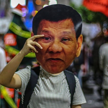 A human rights advocate holds up a mask featuring the image of Philippine President Rodrigo Duterte during a protest in Manila. Photo: AFP