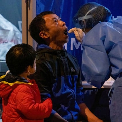 A medical worker wearing collects swab samples from a man during mandatory coronavirus testing in Hong Kong as a boy looks on. Government rules that change frequently are causing families stress. Photo: Isaac Wong/SOPA Images/LightRocket via Getty Images