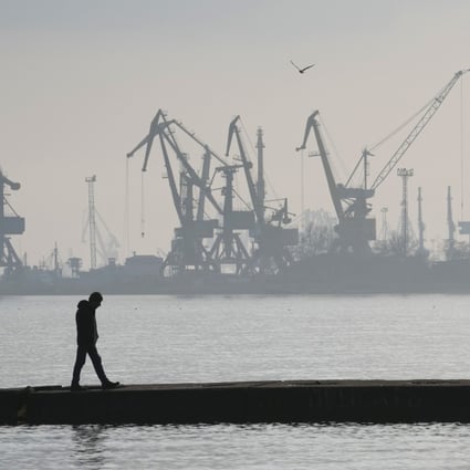 A man walks with harbour cranes in the background, at the trade port in Mariupol, Ukraine on February 23. Photo: AP