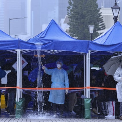 A health worker removes rainwater from a temporary Covid-19 testing tent in Central on February 20. Photo: Nora Tam