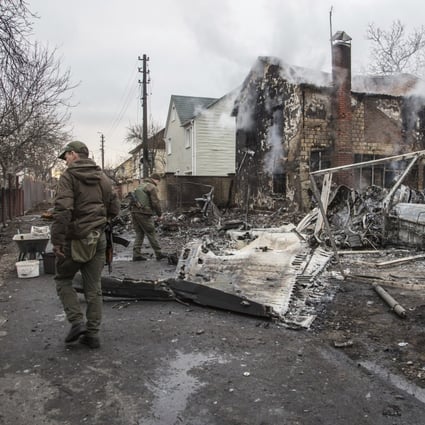 Ukrainian servicemen walk by fragments of a downed aircraft in Kyiv on February 25. Photo: AP