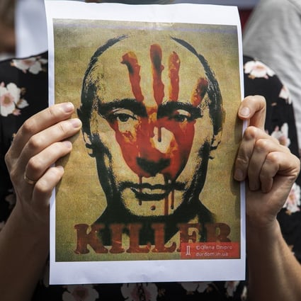 A Ukrainian protester holds up a poster of Russian President Vladimir Putin with the word “killer” during a rally outside the Russian embassy in Bangkok, Thailand in February. Photo: TNS