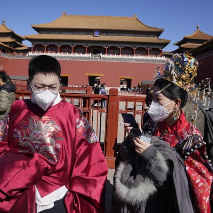 People dressed in period costumes keep their masks on outside the entrance to the Forbidden City in Beijing. Photo: AP
