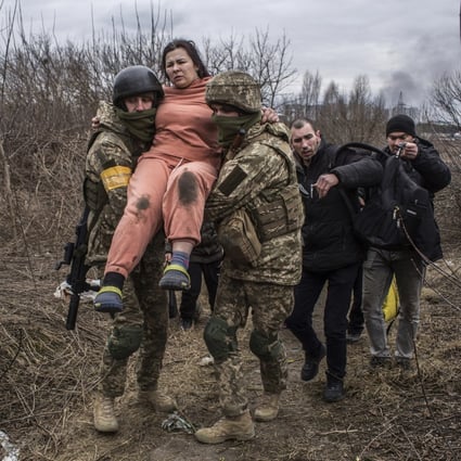 A woman is carried by Ukrainian soldiers while fleeing the town of Irpin, Ukraine on March 6. Photo: AP 