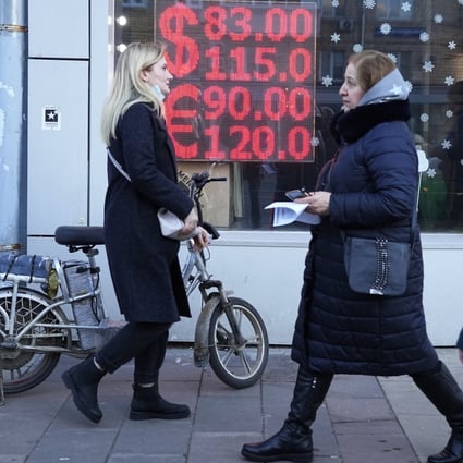 People walk past a currency exchange office in Moscow on February 28. The ripple effects from the West’s sanctions against Russia are driving up commodity prices that were already high. Photo: AP
