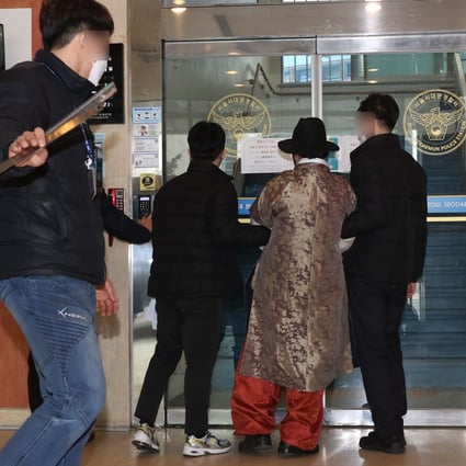 A man wearing a robe and hat being taken into a police station in Seoul, South Korea, on Monday, to be questioned in relation to an attack on Song Young-gil, head of the ruling Democratic Party. Song was taken to hospital with non-life-threatening injuries, according to party officials.  Photo: EPA-EFE