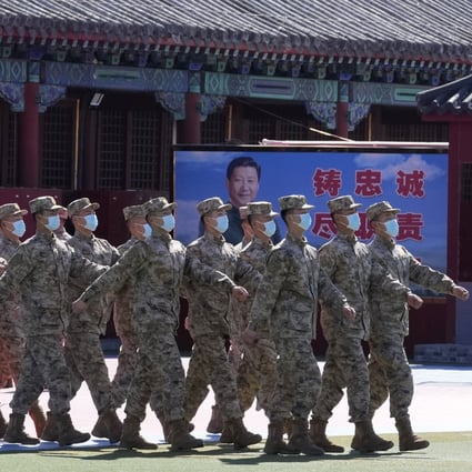 Members of  a  Chinese military honour guard march past a poster showing  President Xi Jinping and slogans calling for loyalty and duty, in Beijing on Saturday. Photo: AP