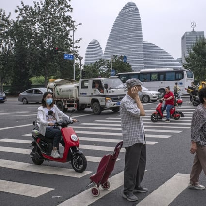 Pedestrians cross a road near Soho China’s Wangjing Soho project in Beijing. Photo: Bloomberg