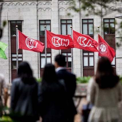 People walk before flags of CK Hutchinson Holdings outside the company’s headquarters in Hong Kong on March 21, 2019. Photo: AFP