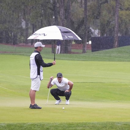 Caddie Ricky Elliott keeps the rain off Brooks Koepka as he studies a putt on the 11th green during the first round of The Players Championship. Photo: USA Today Sports