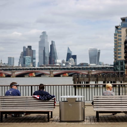 People sit in the sunshine beside the River Thames in London on July 3, 2020. Photo: AFP