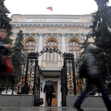 People walk past the Central Bank headquarters in Moscow on March 8. Russia’s central bank assets being held in foreign institutions are now frozen. Photo: Reuters