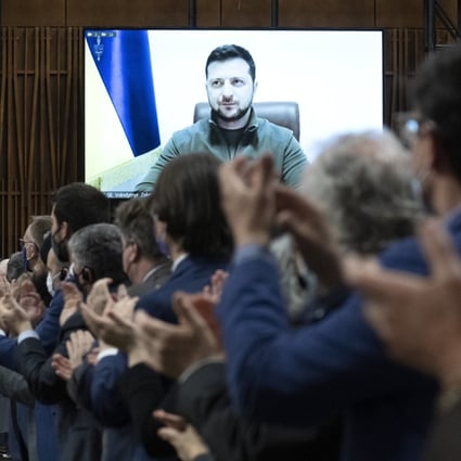 Canadian lawmakers applaud as Ukrainian President Volodymyr Zelensky is shown on a video screen before addressing the House of Commons on Tuesday. Photo: The Canadian Press via AP