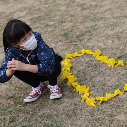 People admire and take pictures of the blossoming yellow Golden Trumpet Tree flowers at Nam Cheong Park in Nam Cheong on March 17. Research suggests people are more likely to engage in healthy behaviours such as wearing masks when they feel empowered to take care of themselves during the pandemic. Photo: Nora Tam