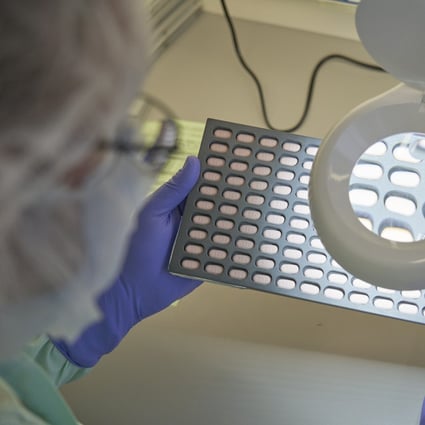 A lab technician visually inspects Paxlovid tablet samples in Freiburg, Germany in December 2021. Photo: Pfizer via AP 