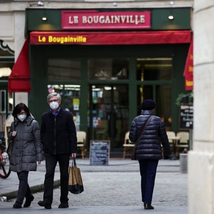 People wear protective face masks as they walk along a street in Paris, France. Photo: Reuters