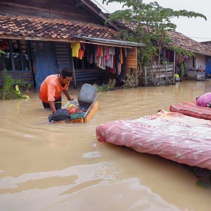 A villager dries items from his flooded house in Sukajaya village in Serang on March 2. The Indonesian city was submerged after days of unusually heavy rainfall earlier this month. Photo: AFP