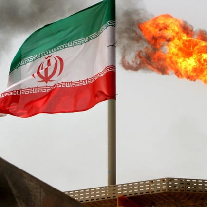 A gas flare on an oil production platform in the Soroush oil fields alongside an Iranian flag in the Gulf. Photo: Reuters