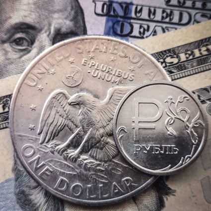 A Russian rouble coin is pictured with US dollar bills and a US$1 coin in Moscow, on March 15. The dollar benefits not just the US but also its users, who create an ecosystem that entrenches its superiority. Photo: AFP