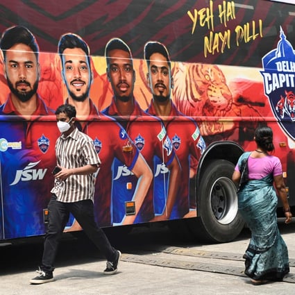 Pedestrians walk past the bus of Indian Premier League’s (IPL) Delhi Capitals in Mumbai. Photo: AFP