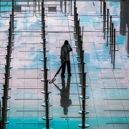 Workers clean an area for arriving passengers at Hong Kong International Airport on March 21. Photo: AFP