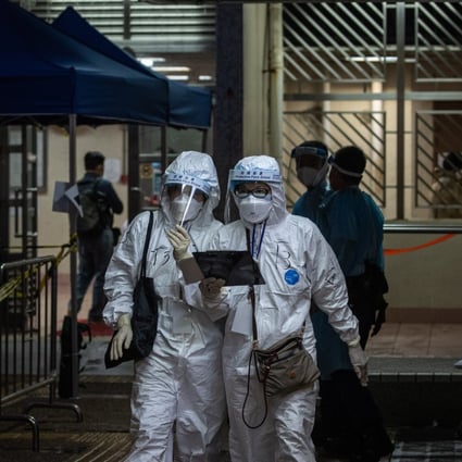 Health workers walk out of a building under lockdown in Hong Kong on March 25. Photo: EPA