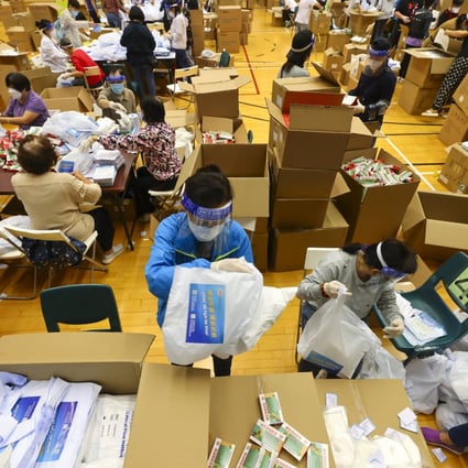Volunteers pack kits of rapid Covid-19 tests, masks and medicine set to be distributed to Hong Kong residents at Tai Wo Hau Sports Centre.  Photo: Dickson Lee
