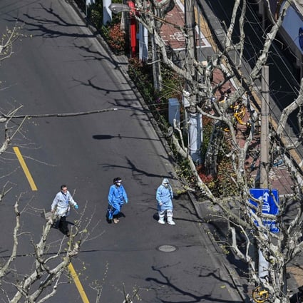 Workers wearing protective gear walk on a street during the second stage of a Covid-19 lockdown in the Jing’an district in Shanghai on April 3, 2022. Photo: AFP