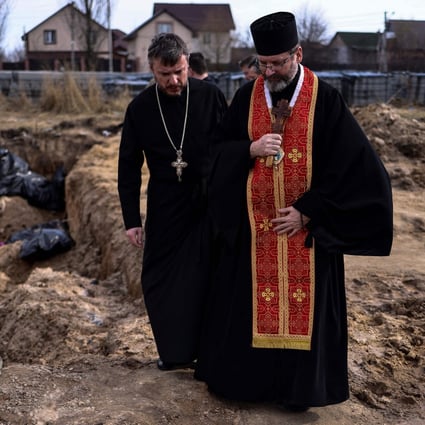 Priests pray over body bags in a mass grave in the garden surrounding the St Andrew church in Bucha, Ukraine, on April 7. Photo: TNS