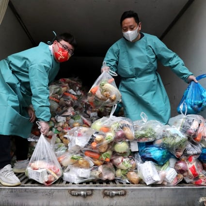 Workers wearing protective gear sort bags of vegetables and groceries on a truck to distribute them to residents at a residential compound, during the lockdown to curb the coronavirus disease (COVID-19) outbreak in Shanghai on April 5, 2022. Photo: China Daily via Reuters