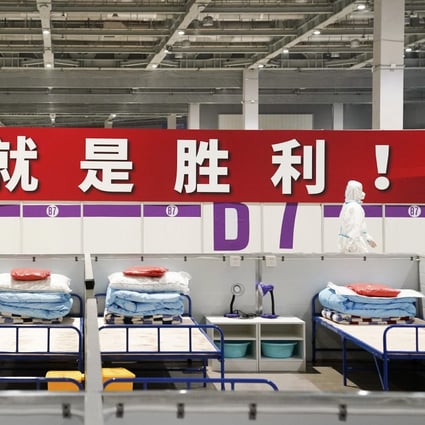A healthcare worker walks past a banner reading “Persistence is victory!” at a makeshift hospital and quarantine facility in Shanghai on Monday. Photo: Xinhua
