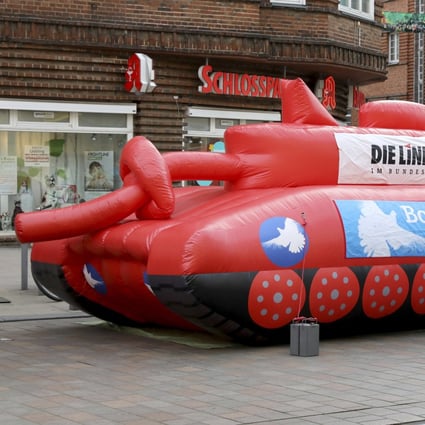 An inflatable tank with a knotted gun barrel stands at Marienplatz in Schwerin, Germany, on April 12. A banner on the tank reads “Bombs don’t create peace”. Photo: AP