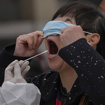 A woman pulls up her mask to get her throat swab at a coronavirus testing site in Beijing on April 6. Photo: AP