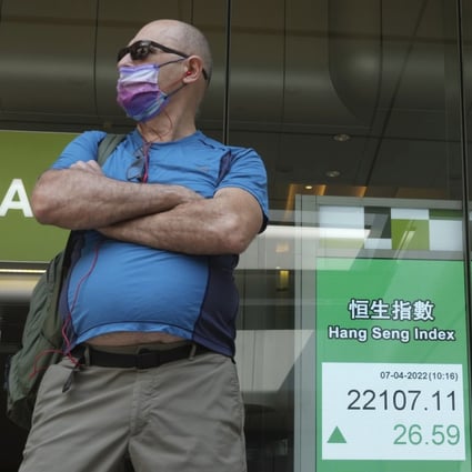 A man stands next to a bank’s electronic board showing the Hong Kong share index. Photo: AP Photo