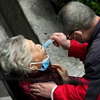 A man helps a woman consume a packet of the traditional Chinese medicine Lianhua Qingwen outside a residential compound in Shanghai on April 5. Photo: Reuters