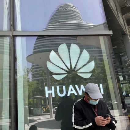 A man uses his smartphone in front of a Huawei logo in Beijing, April 27,  2022. Photo: SCMP/Simon Song