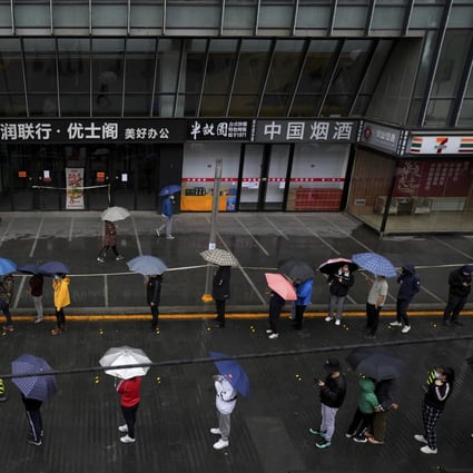 Locked-down residents line up in the rain for Covid-19 testing outside a closed office complex in Beijing. Photo: AP