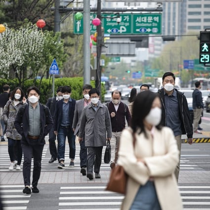 Morning commuters wearing face masks cross a road in Seoul earlier this month. Photo: Bloomberg